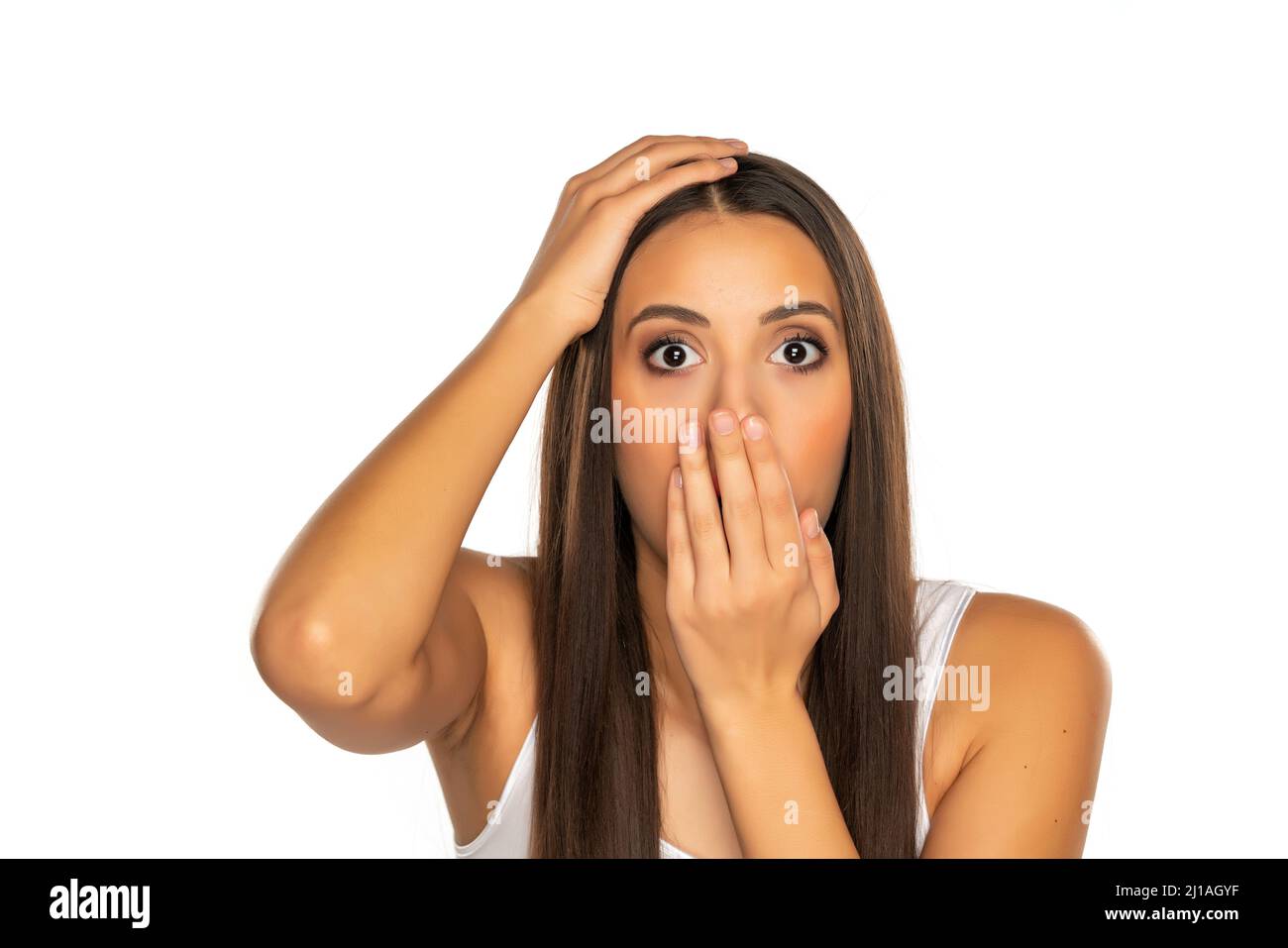 Shocked young woman covers her mouth with her hand on a white background Stock Photo
