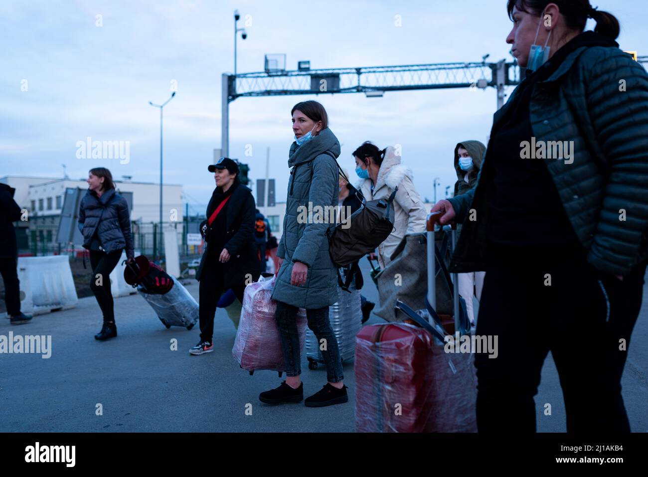 Ukrainian refugees carrying suitcases pass through a border crossing between Poland and Ukraine as they flee the intensifying war in Ukraine, their ho Stock Photo