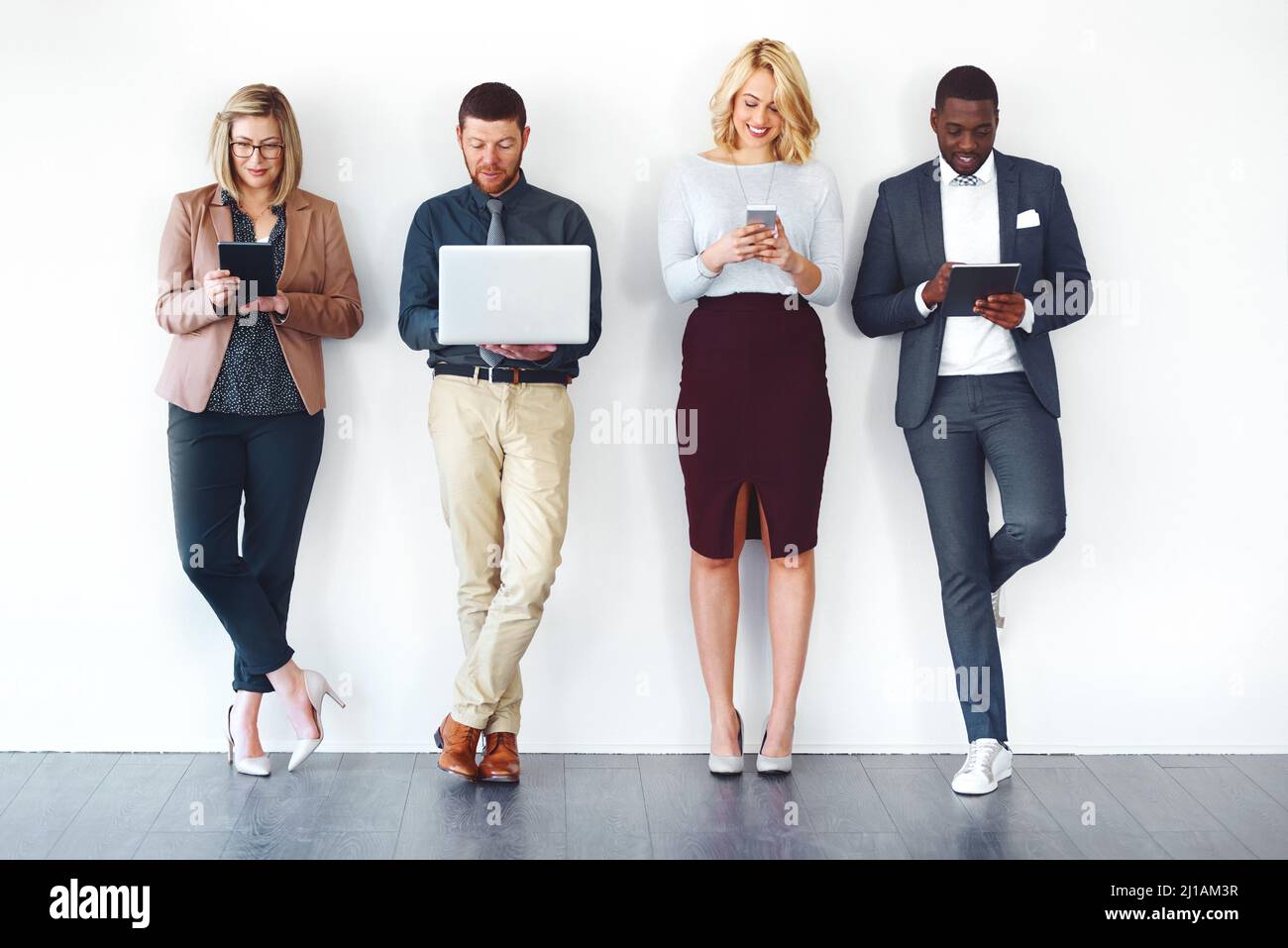 We have all the information needed to succeed. Shot of a group of entrepreneurs using wireless devices against a white background. Stock Photo