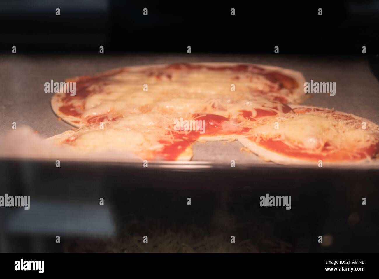 Cheese pizza with strange shape being cooked on a domestic oven Stock Photo