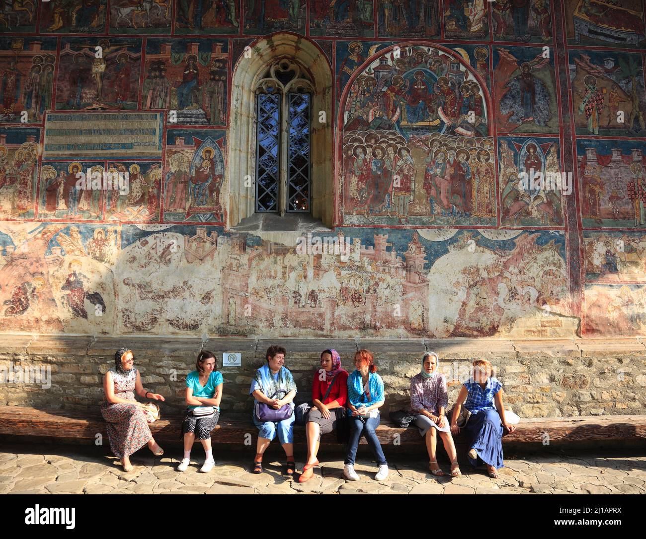 Rumänische Pilger sitzen vor der Freskenwand in Humorului, Romania, Kloster Humor ist ein rumänisch-orthodoxes Frauenkloster und befindet sich etwa 5 Stock Photo