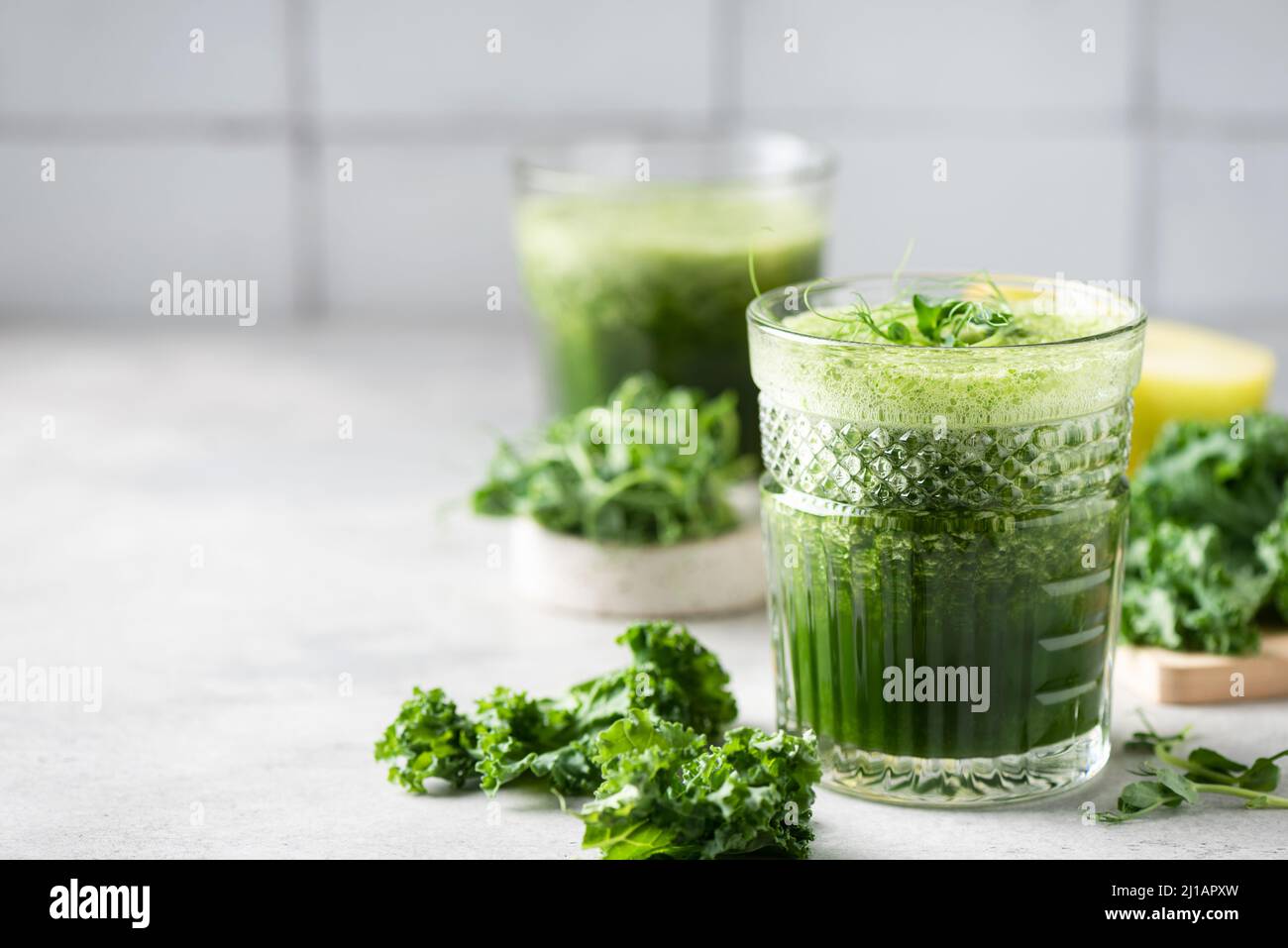 Vegan Green detox juice or smoothie in glass on grey concrete kitchen table. Copy space for text or design Stock Photo