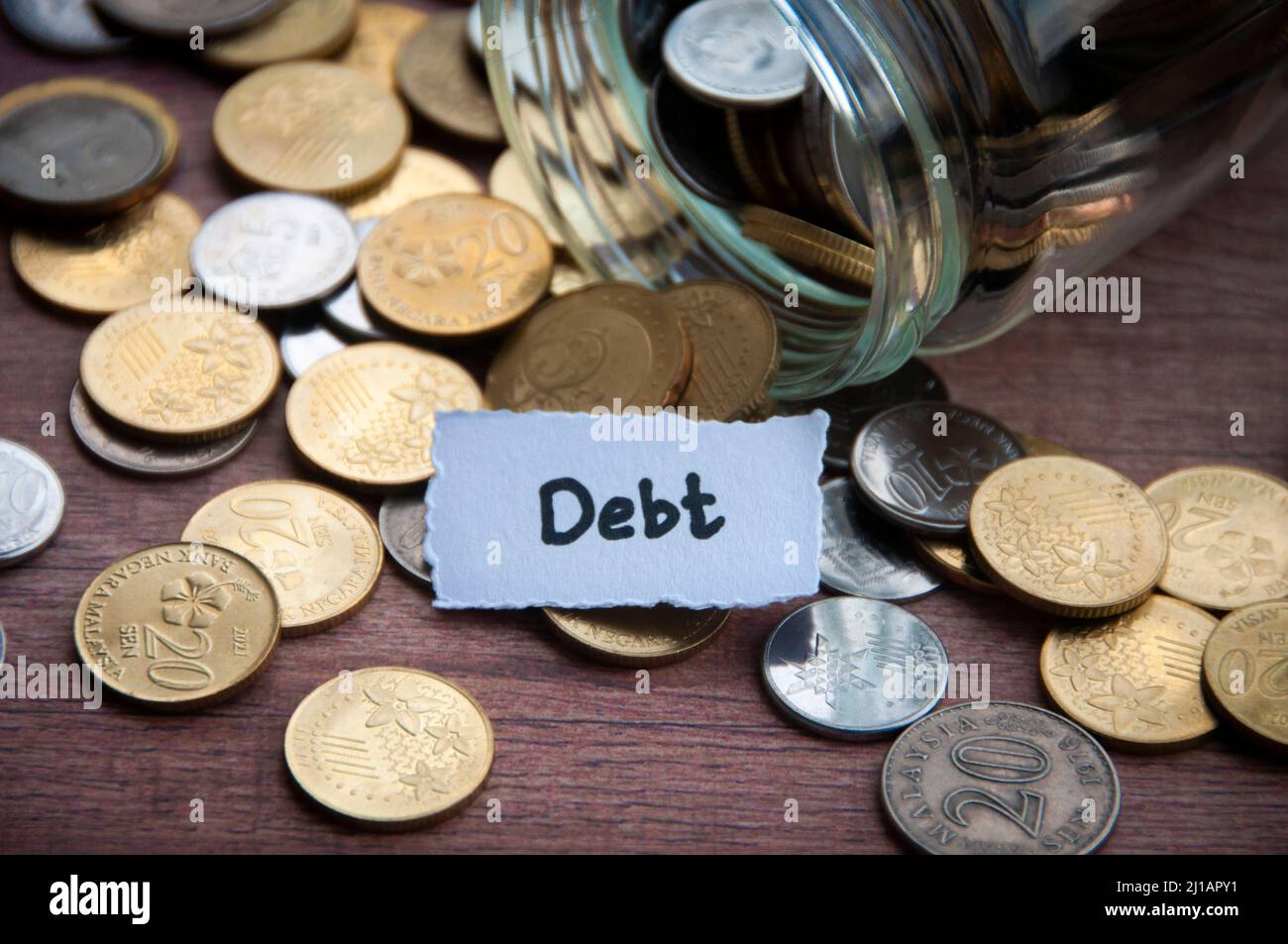 Debt text on torn paper with coins and wooden table background Stock ...