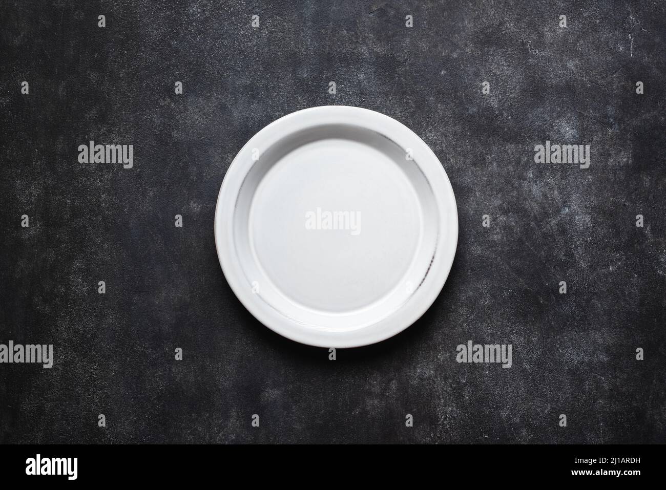 Empty ceramic plate on black concrete background texture. Top view ...