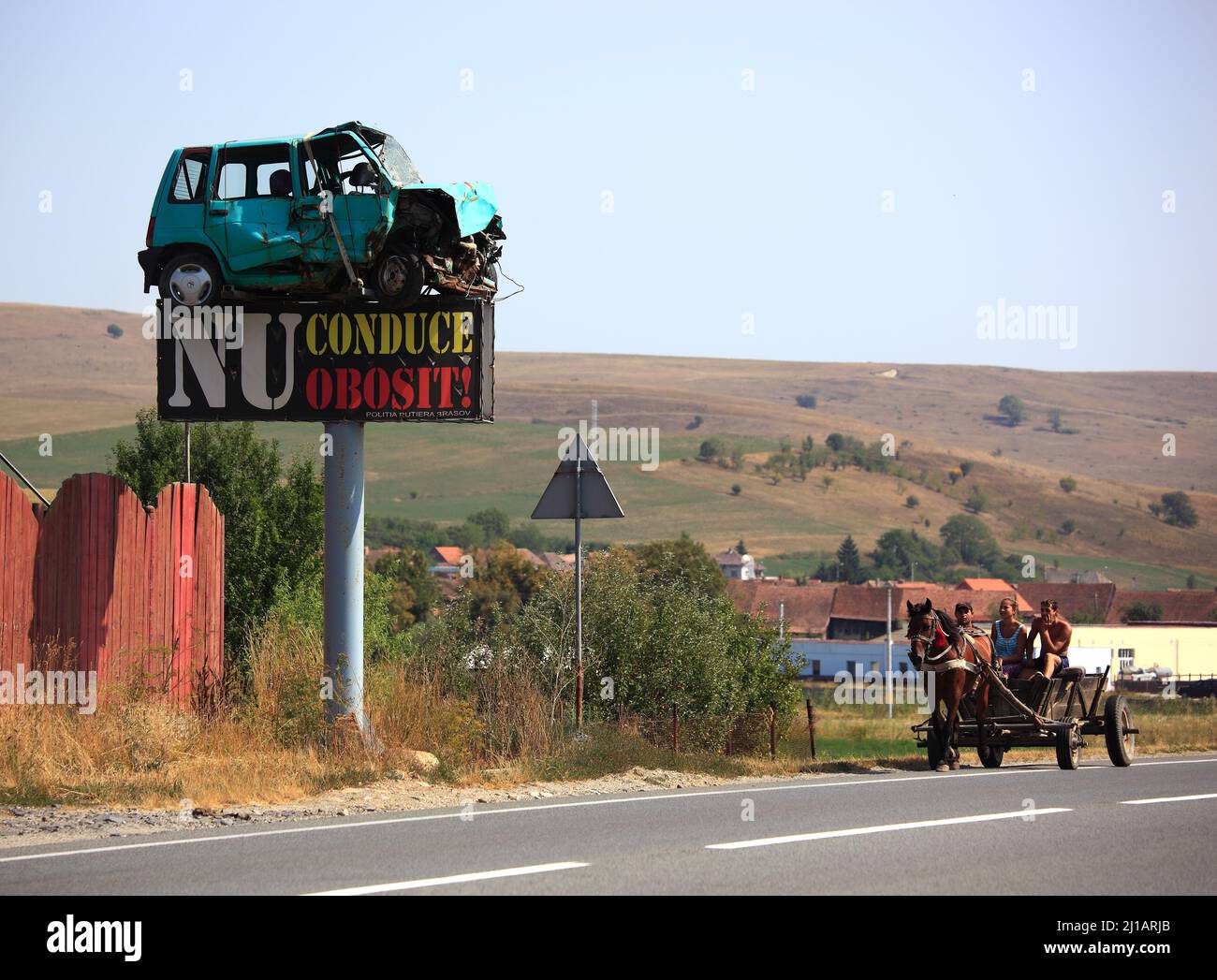 Straßenverkehr in Siebenbürgen, Rumänien, als Warnung wurde ein Unfallwagen als Verkehrsschild montiert, Pferdegespann auf der Straße  /  Road traffic Stock Photo