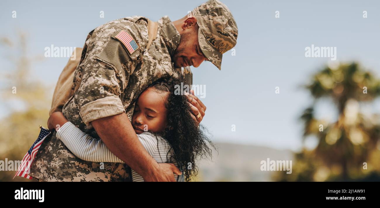 Affectionate military reunion between father and daughter. Emotional military dad embracing his daughter on his homecoming. Army soldier receiving a w Stock Photo