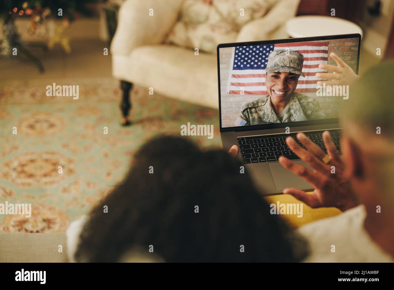 Cheerful female soldier smiling happily while video calling her husband and children from the military base. American military family communicating on Stock Photo