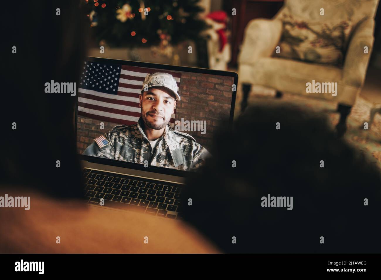 Military man video calling his family at Christmas. American soldier communicating with his family on a laptop. Military family having an online holid Stock Photo