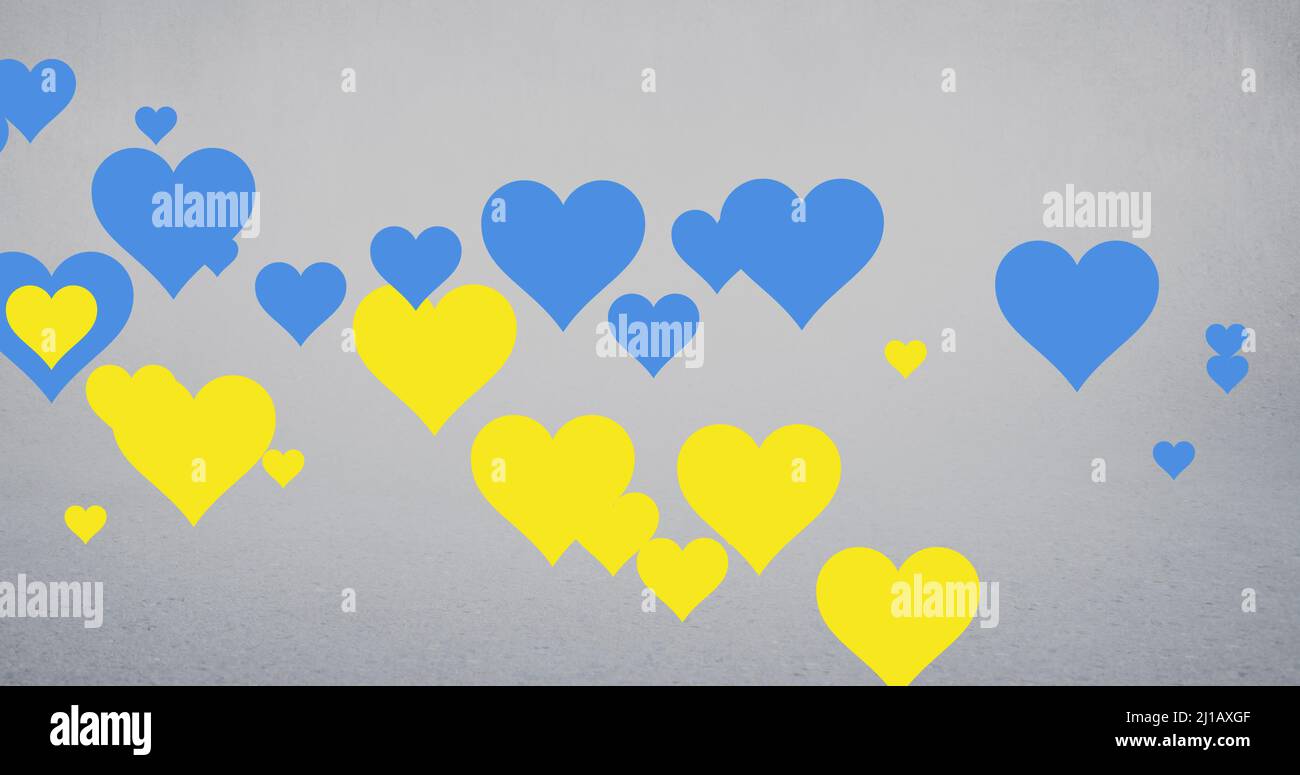 Image of blue and yellow hearts floating over grey background Stock Photo