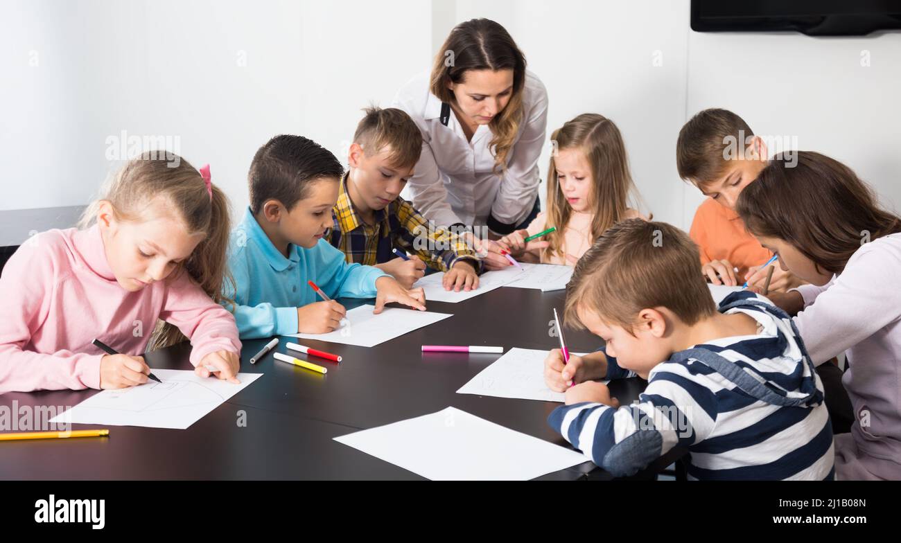 Little kids with teacher drawing in classroom Stock Photo - Alamy