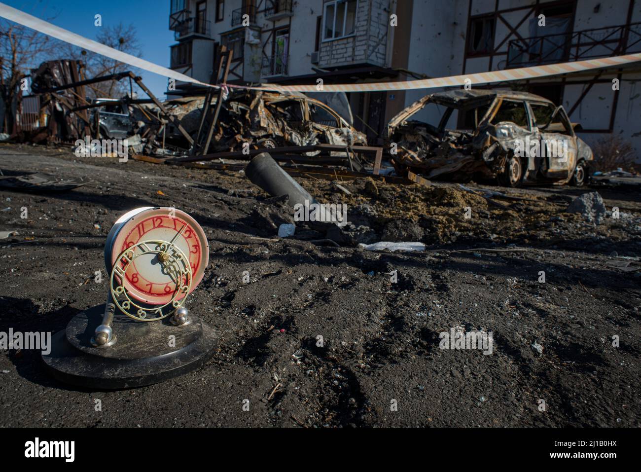 A clock, which was stopped at about 5 AM, and  blown out from the apartment house by the explosion of a russian missile. A part of the missile body, and burned cars. Kharkiv, Ukraine Stock Photo