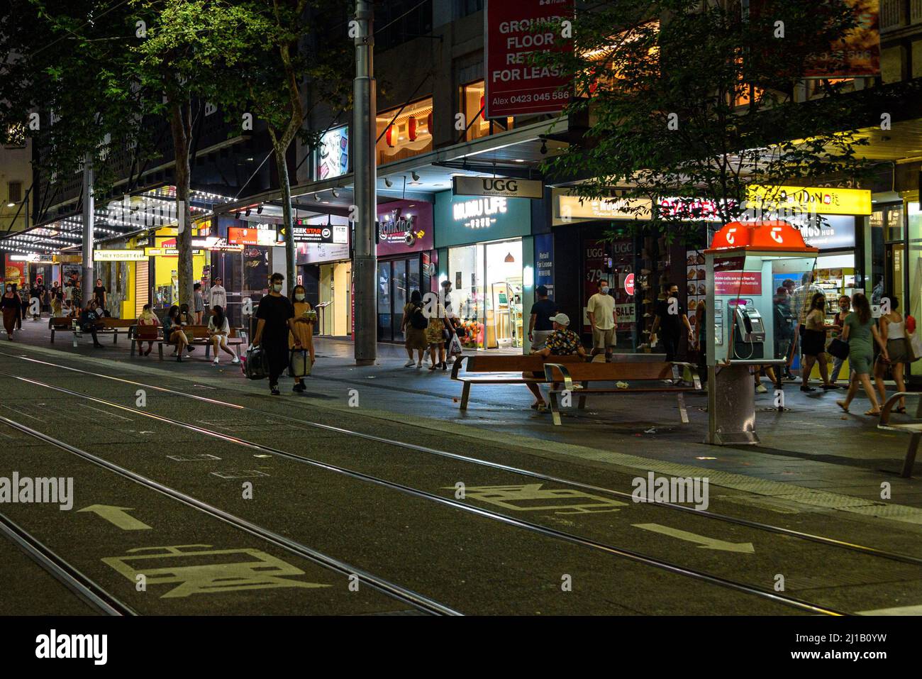 People walking along George Street at night in the Sydney CBD Stock Photo