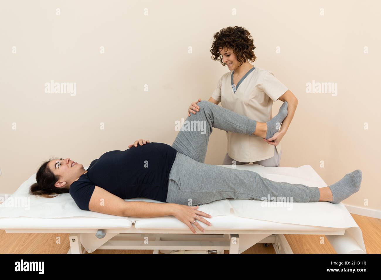 A pregnant woman lying on a massage table while a physiotherapist