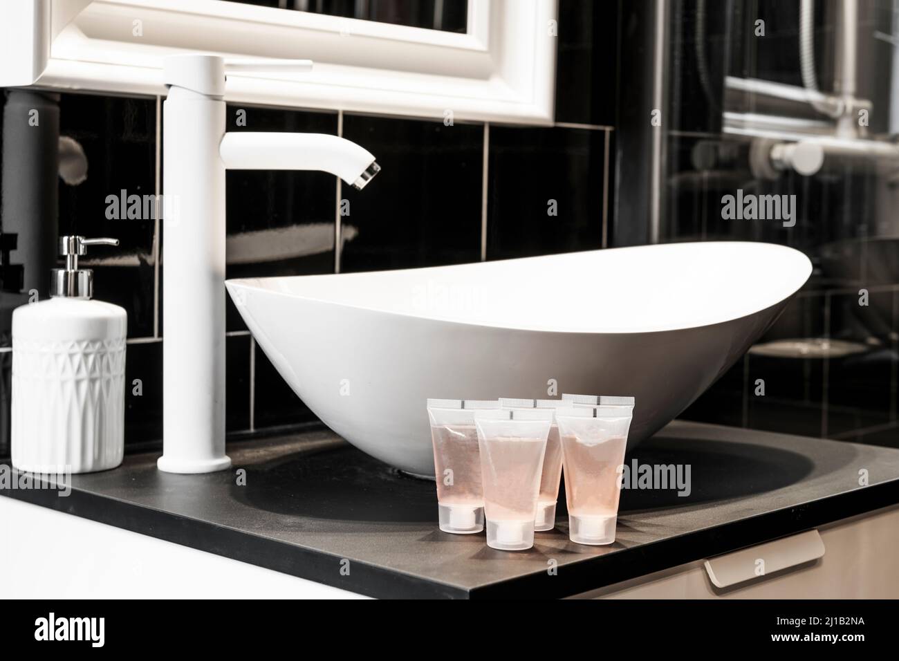 White porcelain sink with matching faucet and black tile on the