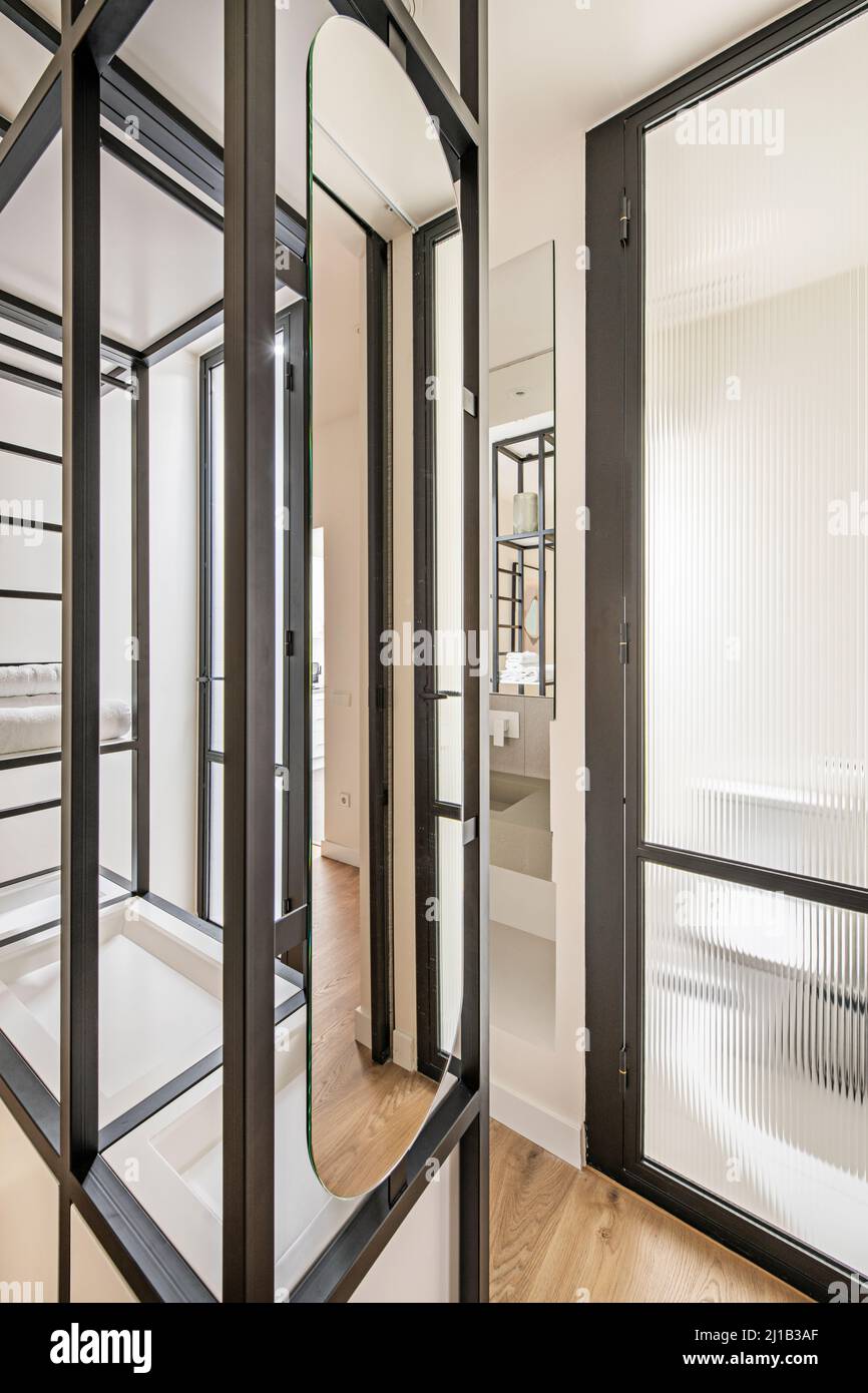 black metal shelves in bedroom with en suite bathroom with sink and mirror Stock Photo