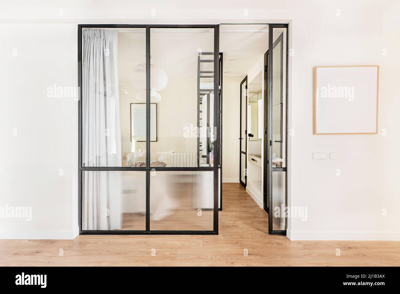 Black metal and glass wall of a bedroom with en-suite bathroom in a vacation rental apartment Stock Photo