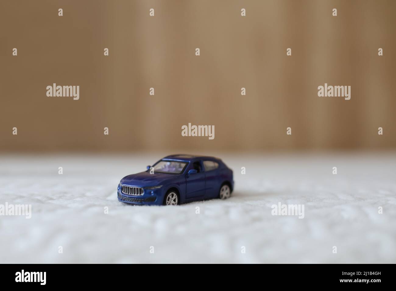 Miniature blue plastic toy car on textile material macro shot. close-up  Stock Photo