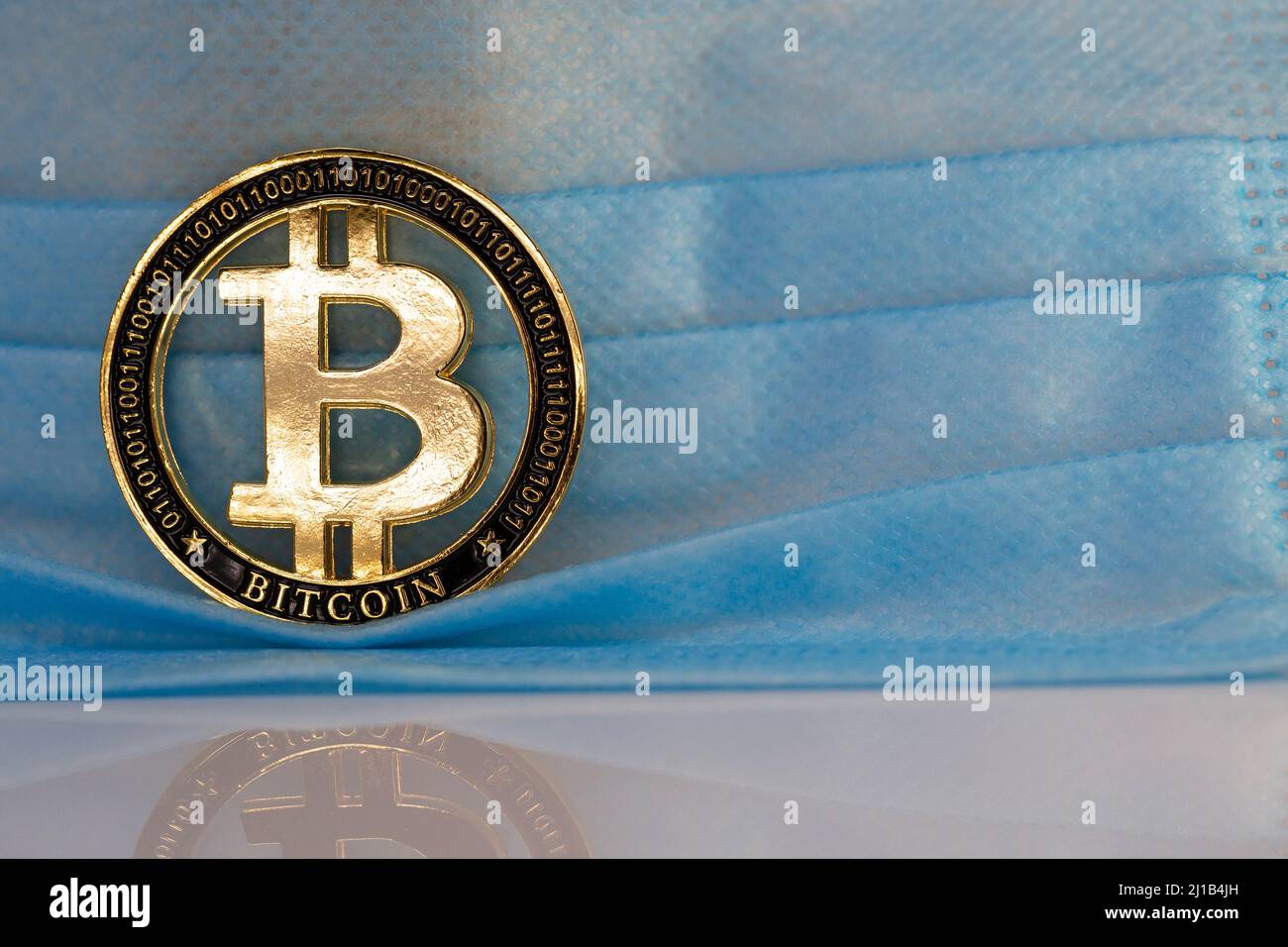 Bitcoin BTC cryptocurrency physical coin placed next to face mask. Stock Photo