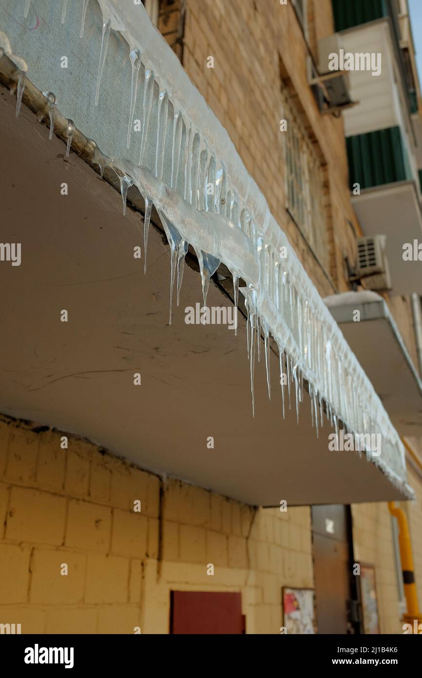 Icicles hang from front porch. Cold winter is here, spring is coming. Icicles are dangerous. Stock Photo