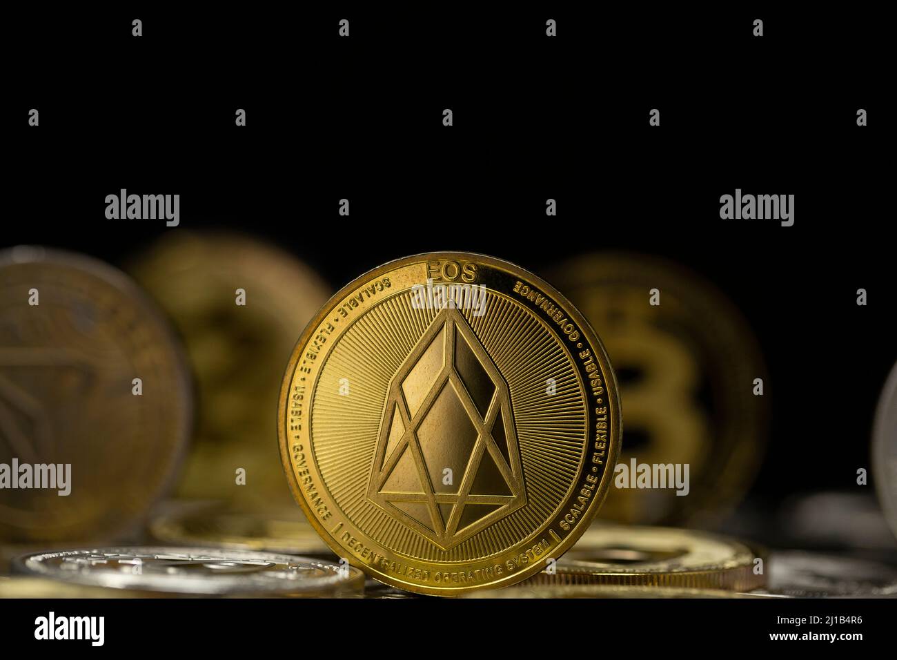 EOS cryptocurrency physical coin placed on variety of altcoins in the black background Stock Photo