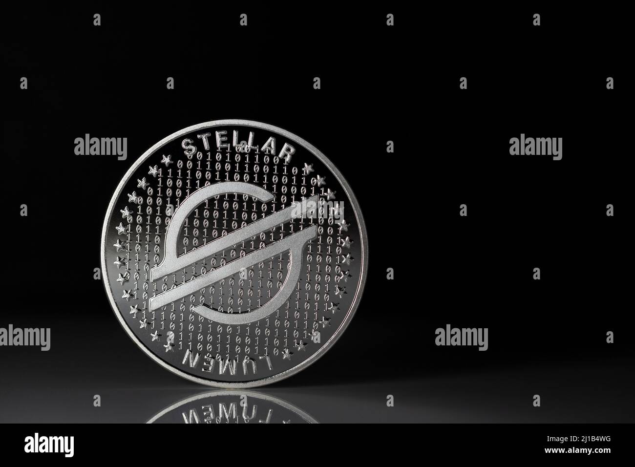 Stellar XLM cryptocurrency physical coin placed on reflective surface and black background Stock Photo