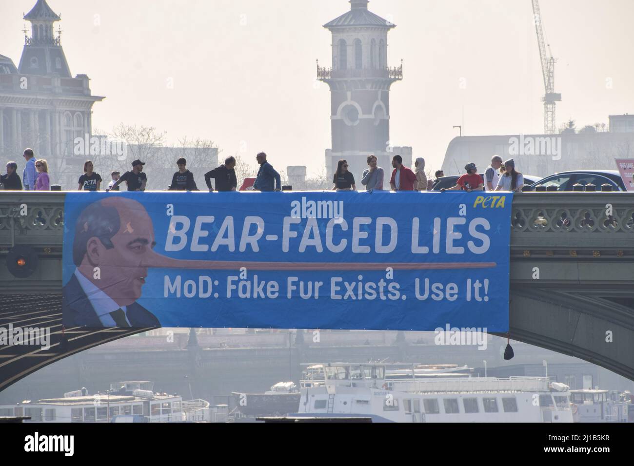 London, UK. 24th March 2022. PETA activists hung a huge banner on Westminster Bridge calling out the Ministry of Defence and defence minister Ben Wallace for misleading the public about the suitability of faux bear fur for Queen’s Guards’ caps and the killing of bears for the caps. Currently, the MOD uses real bear fur to make the caps, and it takes one bear to make just one cap. PETA helped develop a suitable faux fur alternative, which the MOD has so far refused to use. Credit: Vuk Valcic/Alamy Live News Stock Photo