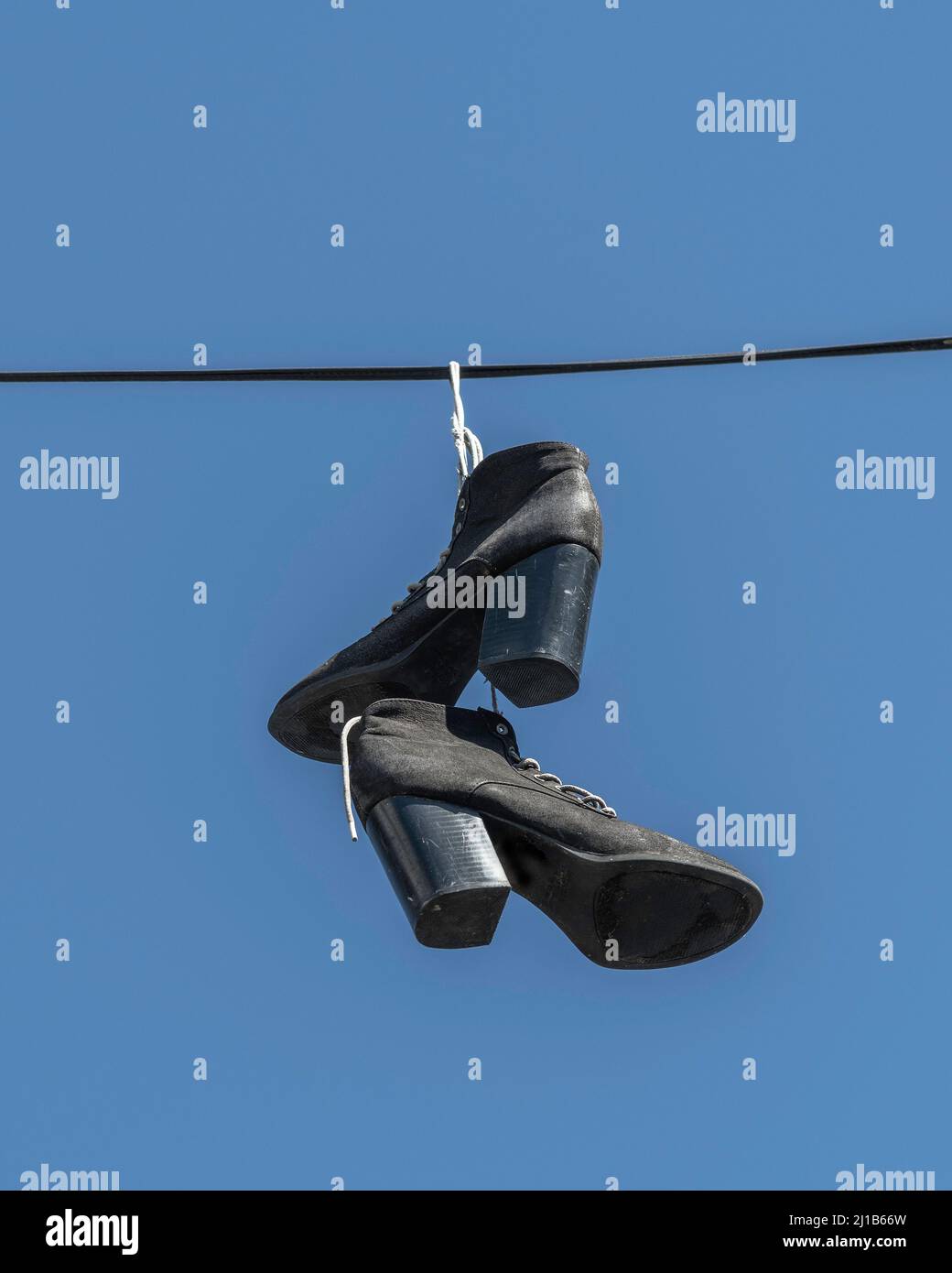 A pair of women's boots hang on a wire in Los Angeles, CA. Stock Photo