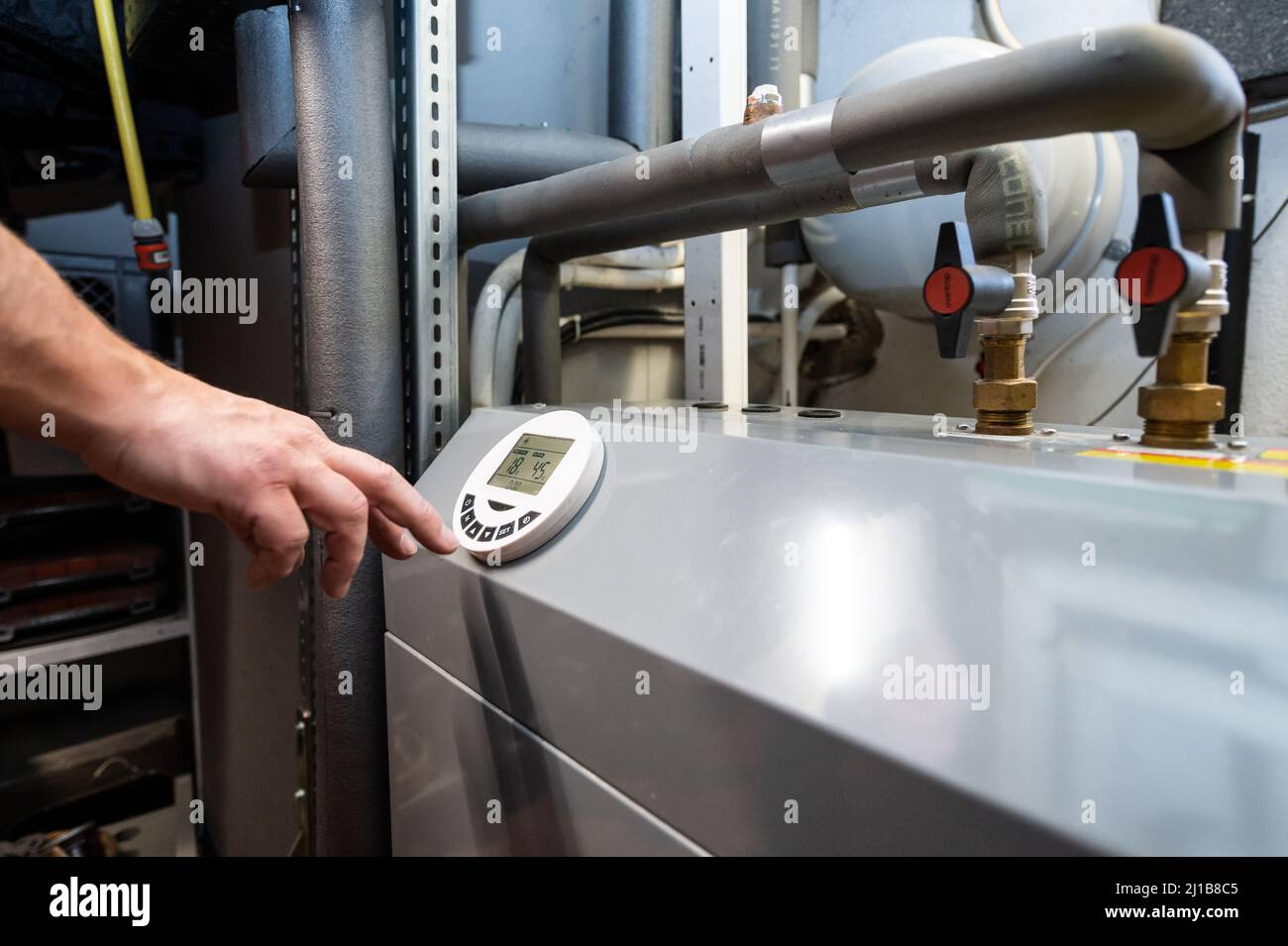 24 March 2022, Baden-Wuerttemberg, Rottweil: A man operates an air-source heat pump located in the basement of a residential building. The heat pump is considered the environmentally friendly and future-proof alternative to oil and gas heating. Photo: Silas Stein/dpa Stock Photo