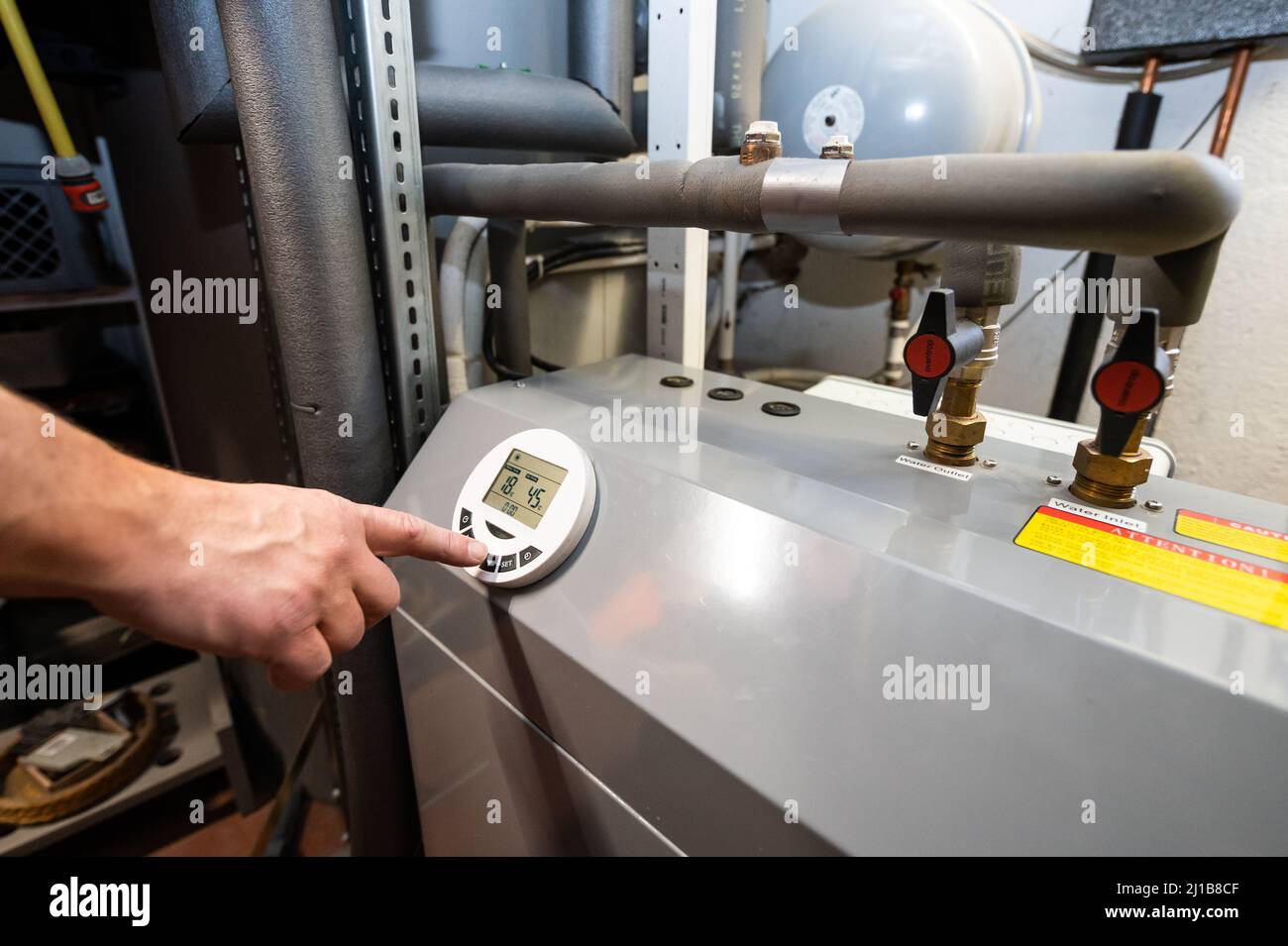 24 March 2022, Baden-Wuerttemberg, Rottweil: A man operates an air-source heat pump located in the basement of a residential building. The heat pump is considered the environmentally friendly and future-proof alternative to oil and gas heating. Photo: Silas Stein/dpa Stock Photo