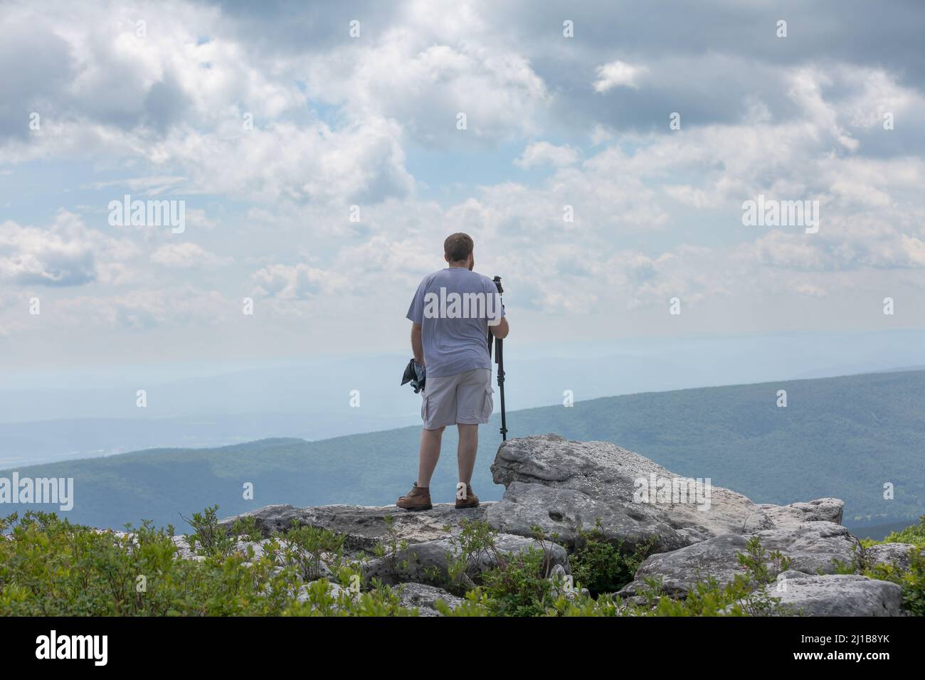 A rear view of a man carrying a photography tripod at the Bear Rocks in ...