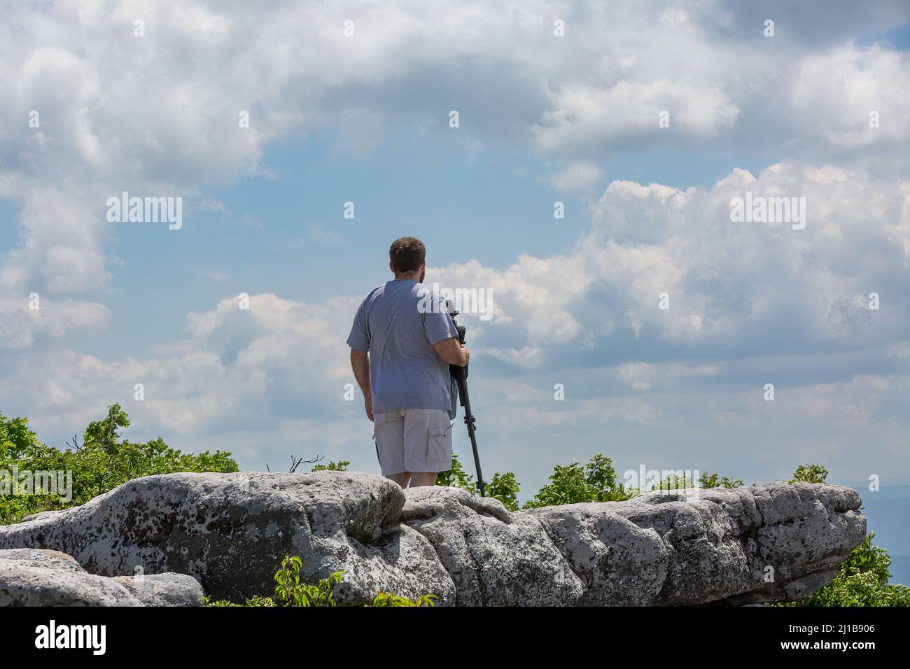 A rear view of a man carrying a photography tripod at the Bear Rocks in ...