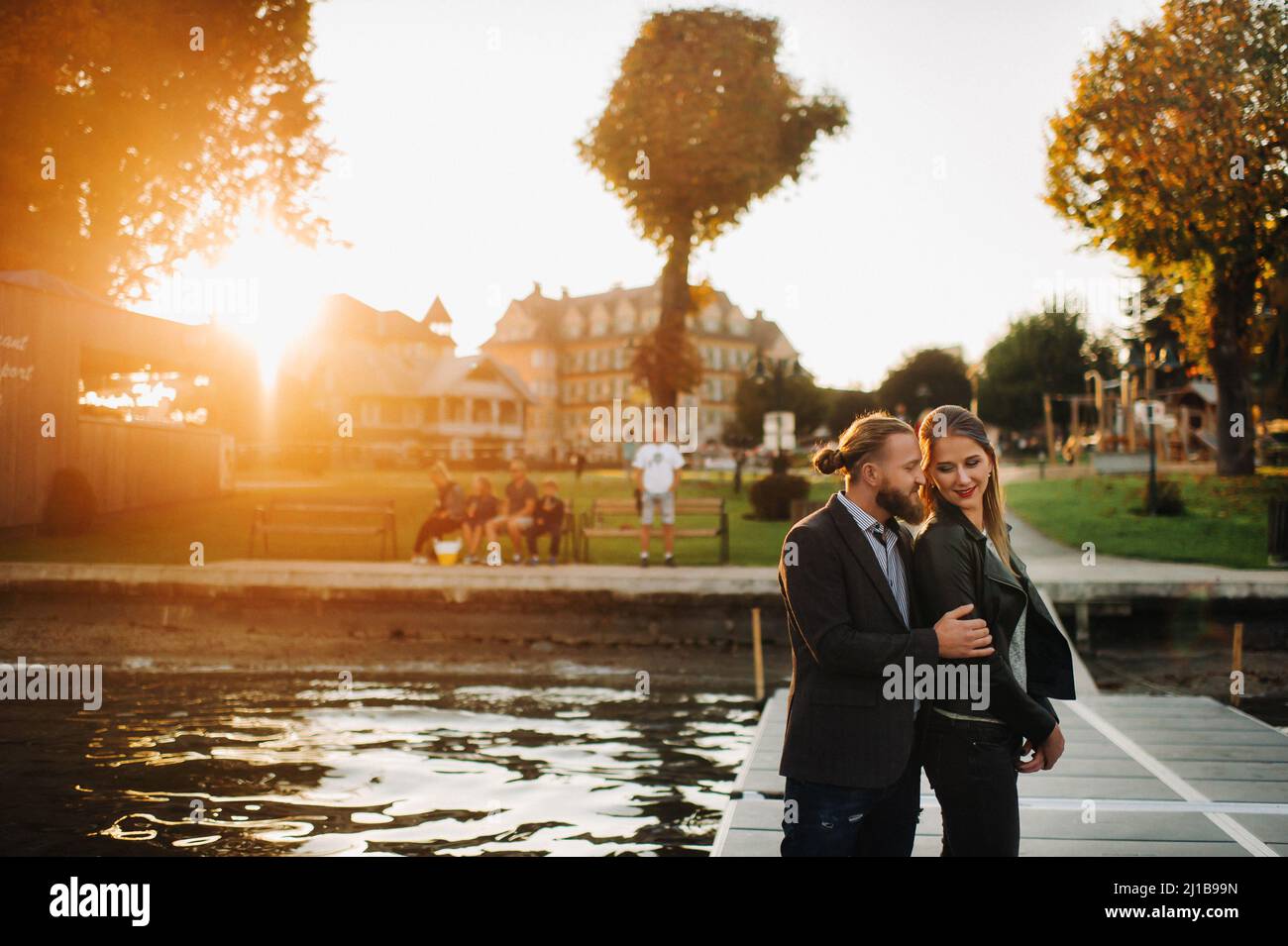a family of two stands on a pier in Austria's old town at sunset .A man and a woman embrace on the embankment of a small town in Austria.Europe.Felden Stock Photo