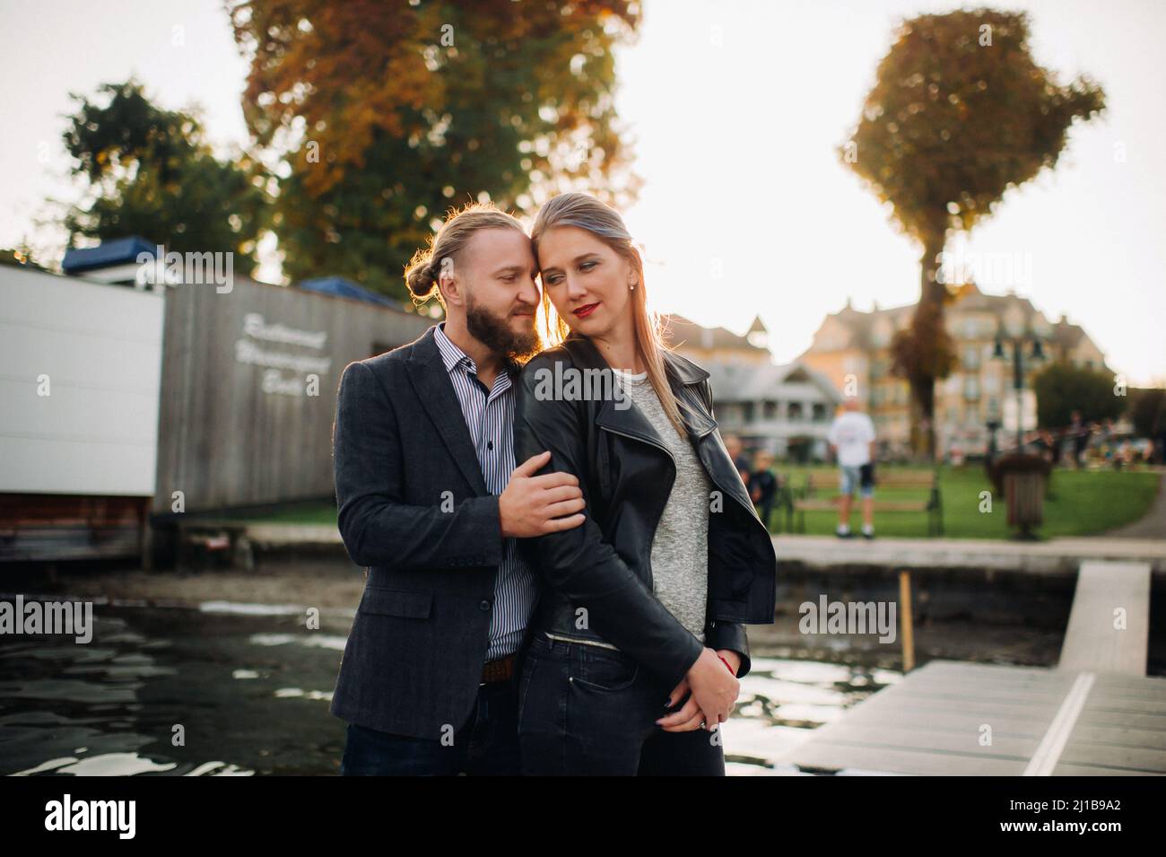 a family of two stands on a pier in Austria's old town at sunset .A man and a woman embrace on the embankment of a small town in Austria.Europe.Felden Stock Photo