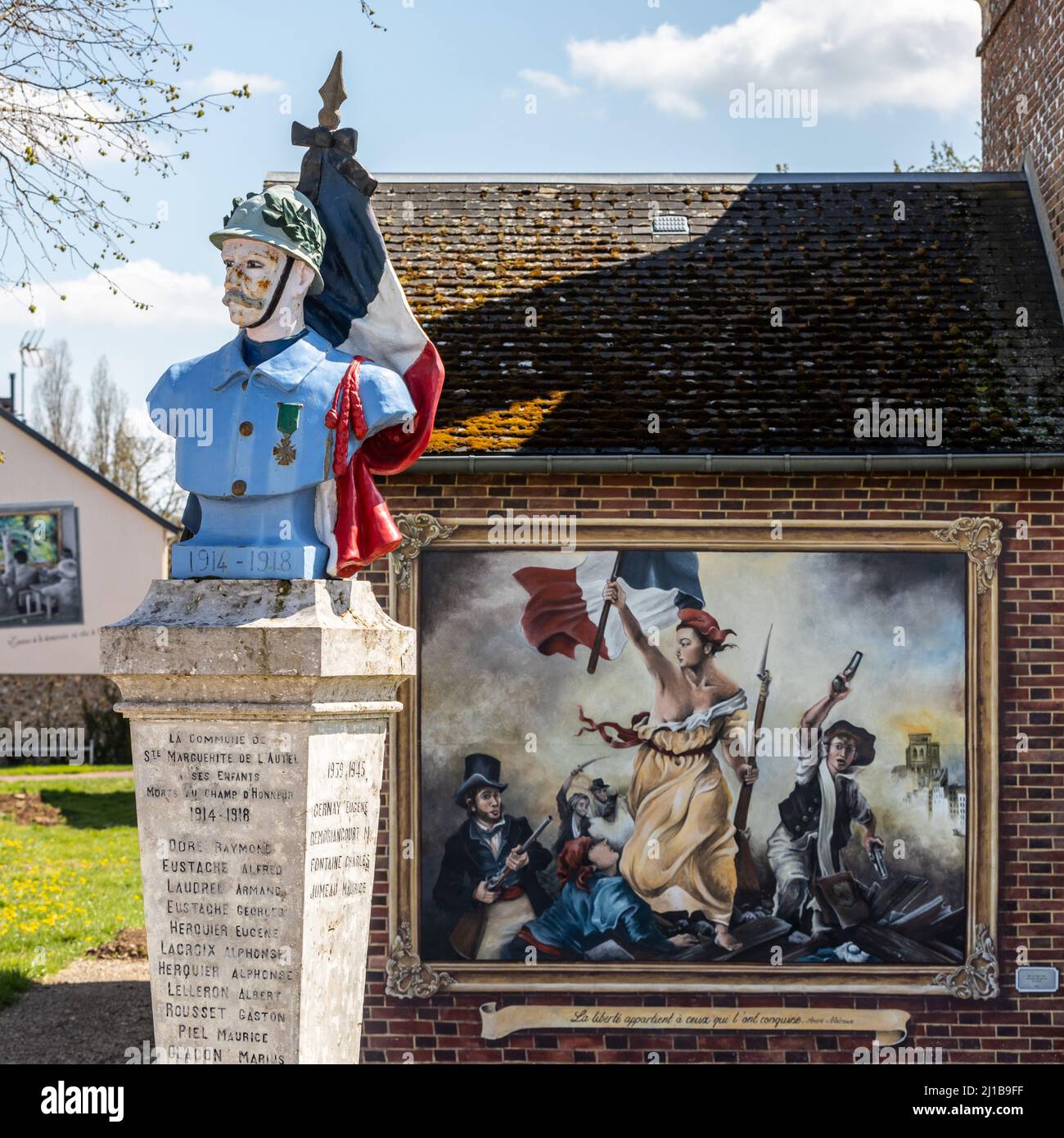 WAR DEAD MONUMENT WITH THE FRENCH FLAG IN HOMAGE TO SOLDIERS OF THE FIRST WORLD WAR AND REPRESENTATION OF A PAINTING EVOKING LIBERTY GUIDING THE PEOPLE AND VALUES OF THE REPUBLIC, SAINTE-MARGUERITE-DE-LÕAUTEL, EURE, FRANCE Stock Photo