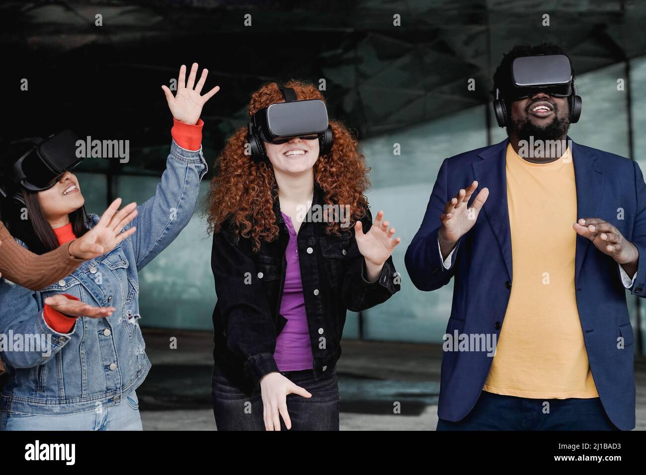Metaverse futuristic entertainment: Young multiracial people having fun with virtual reality glasses - Focus on curly girl gadget Stock Photo