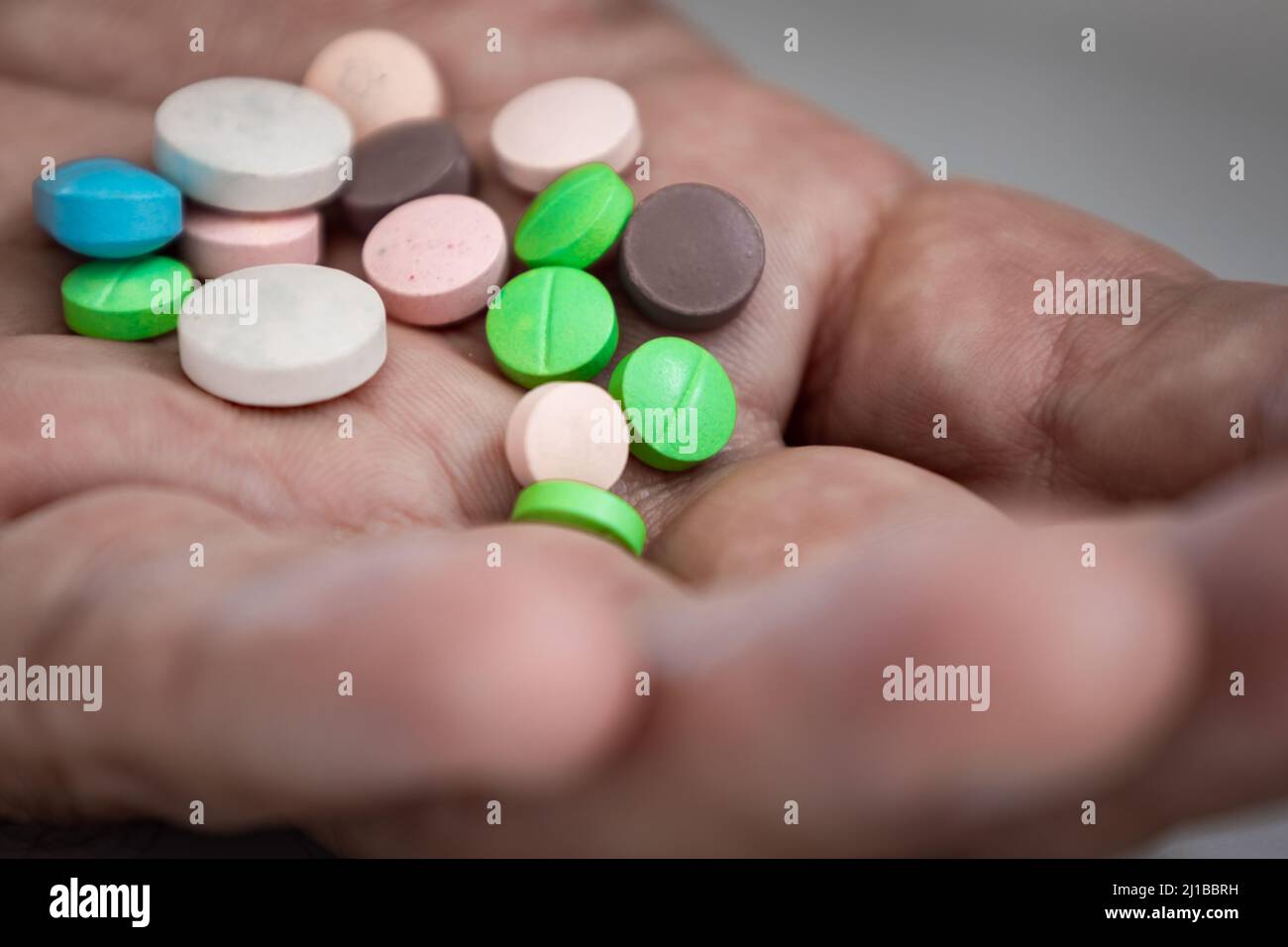 Several colored pills on the palm of the hand. Prescription drug overdose concept. Stock Photo