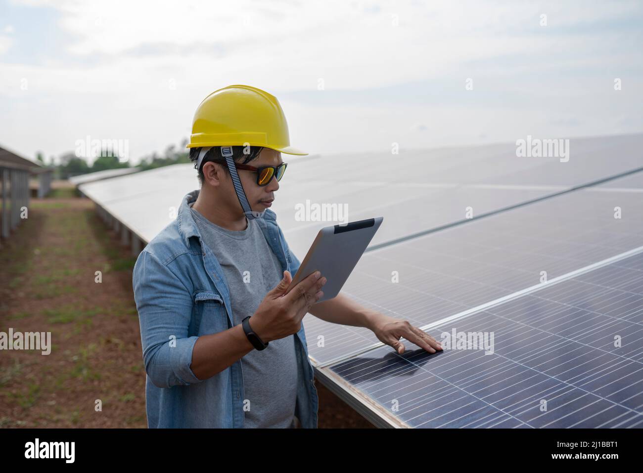 The technician uses a tablet to check the precision of solar energy to generate renewable energy. Stock Photo