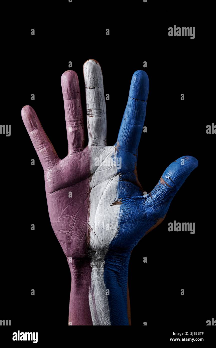 closeup of the raised hand of a person with the transgender pride flag painted in it, on a black background Stock Photo