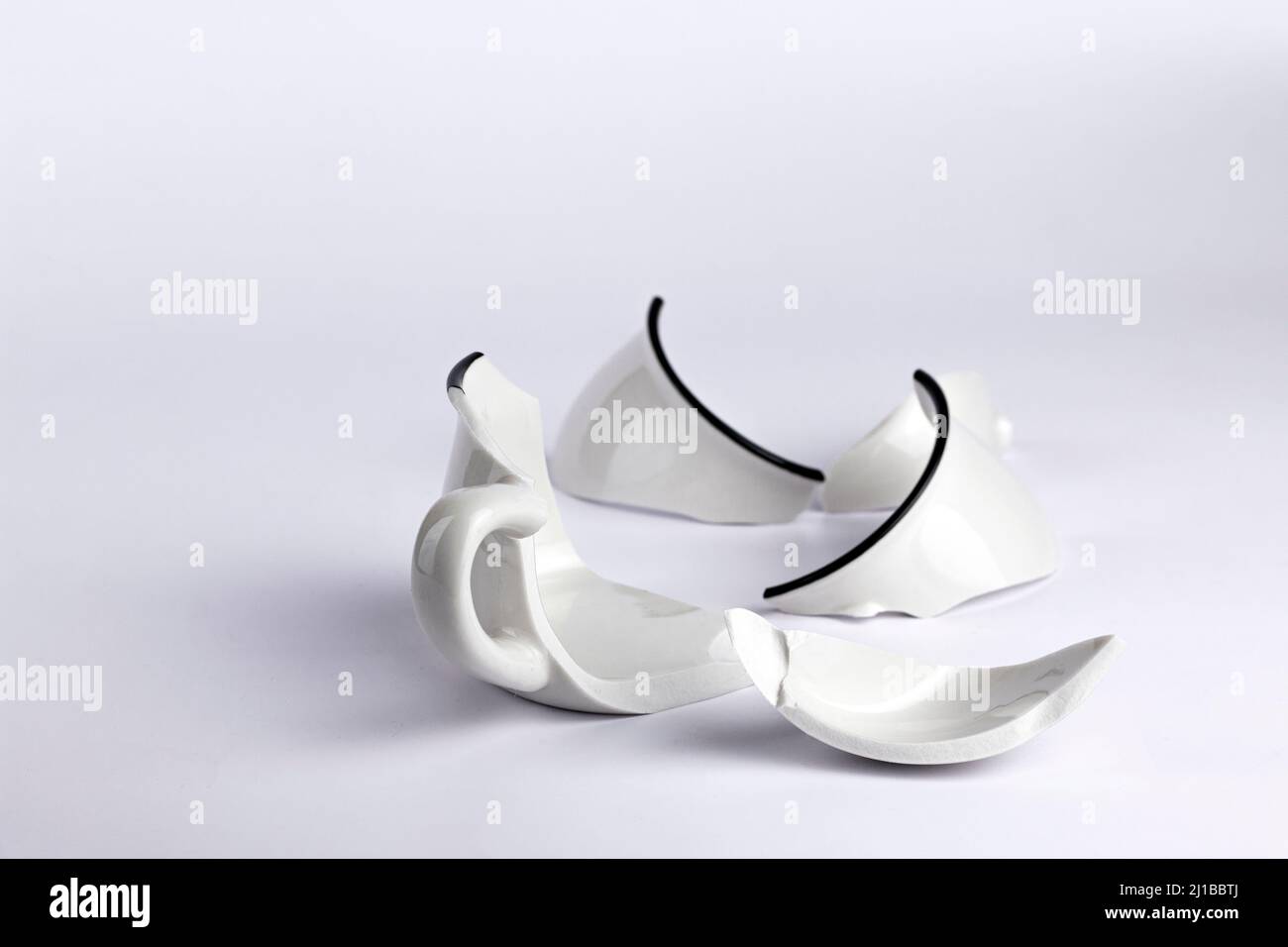 Broken white cup on white background. Concept disintegration, mockup Stock Photo