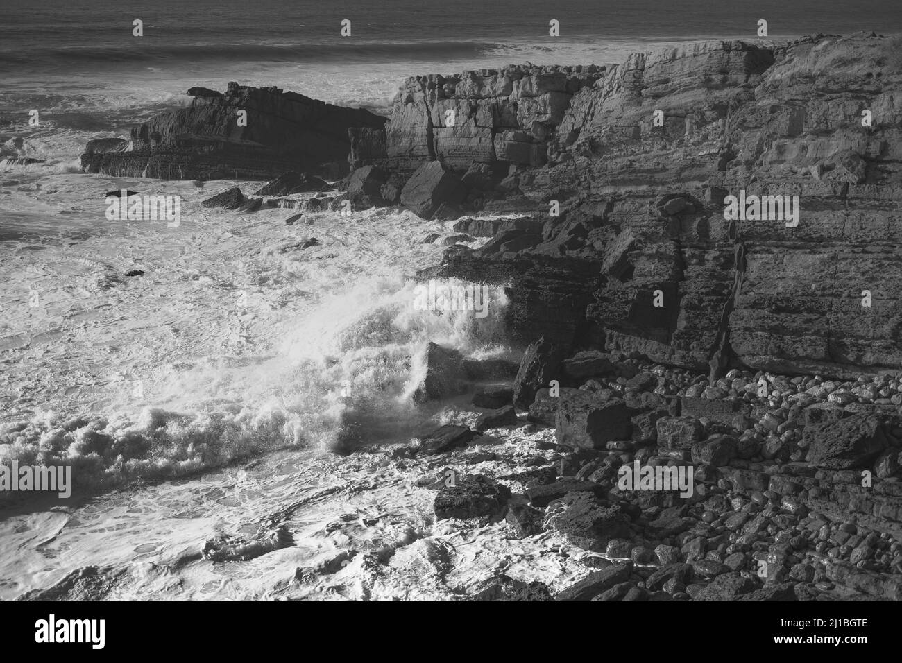 A black and white shot of ocean waves hitting the rocky shore Stock ...