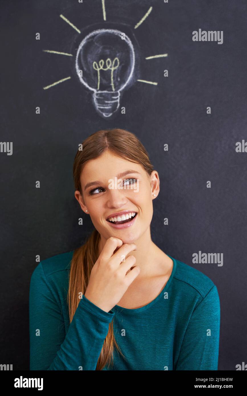 Using illustrations to teach her students. Cropped shot of an attractive young woman standing in front of a blackboard. Stock Photo