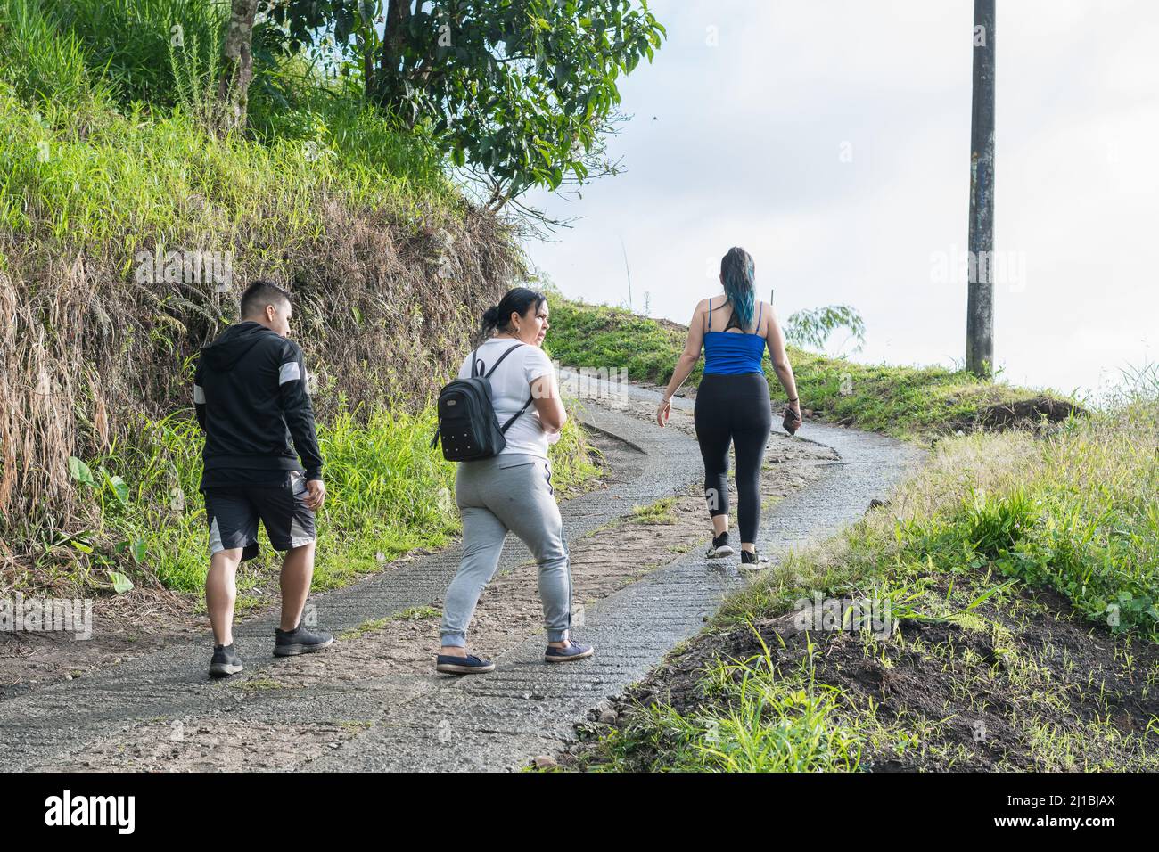 latin family walking in the colombian mountains, mother with her two children going for a morning walk on an ecological trail, exercising her body loo Stock Photo