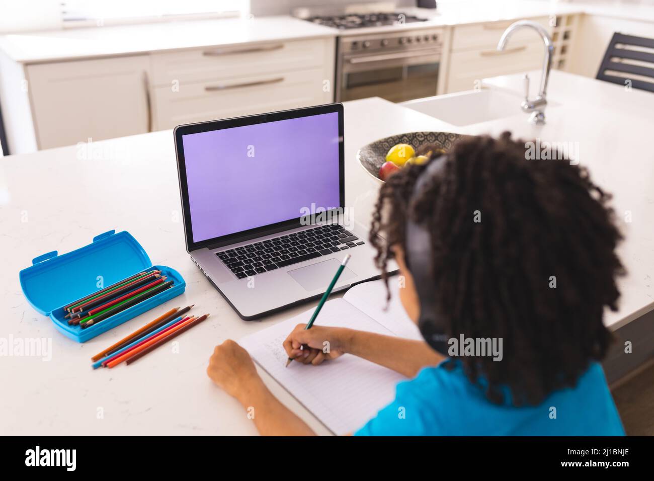 Hispanic boy attending online classes through laptop while sitting at dining table Stock Photo