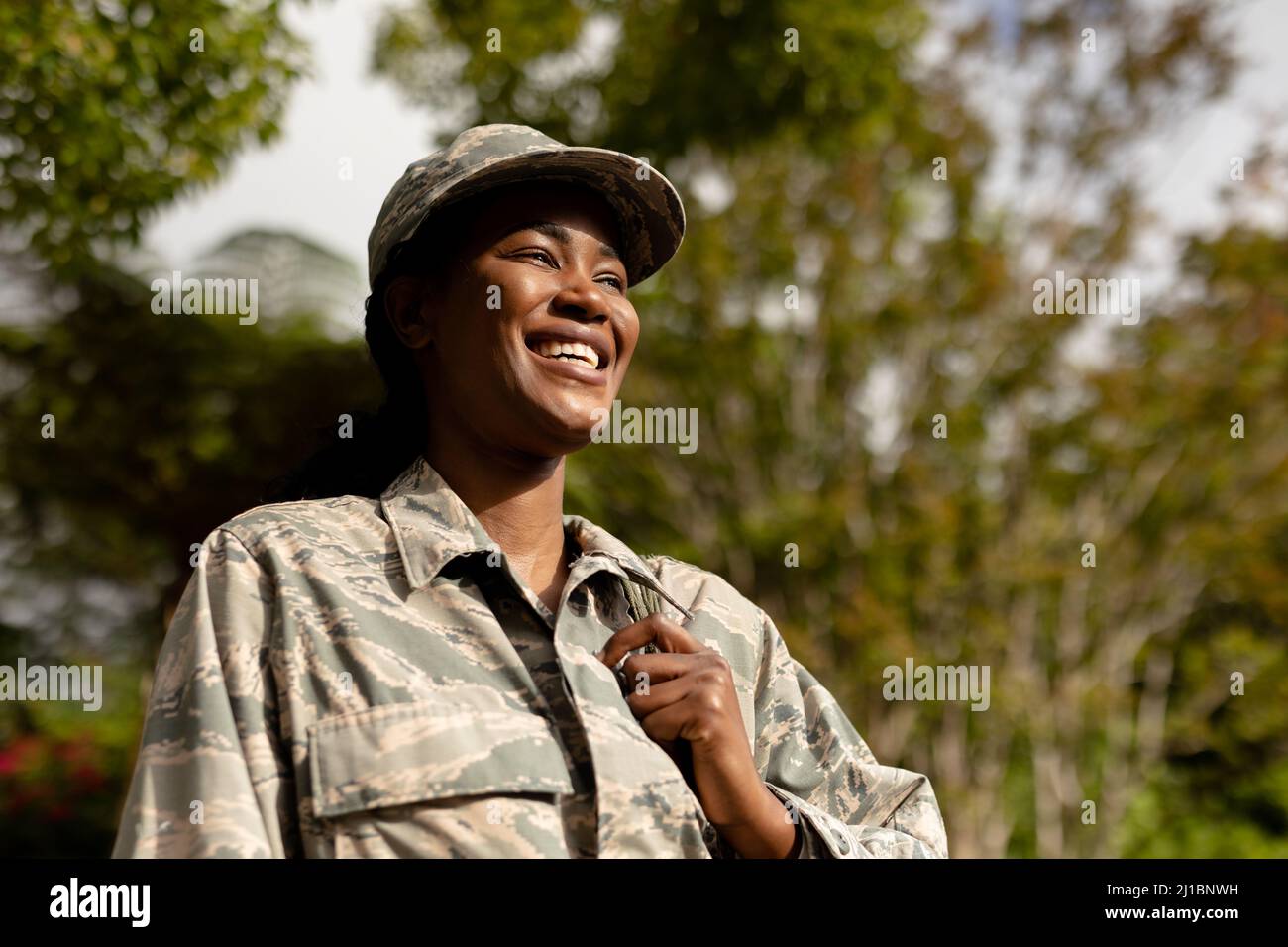 Happy female mid adult african american soldier with backpack outside house Stock Photo