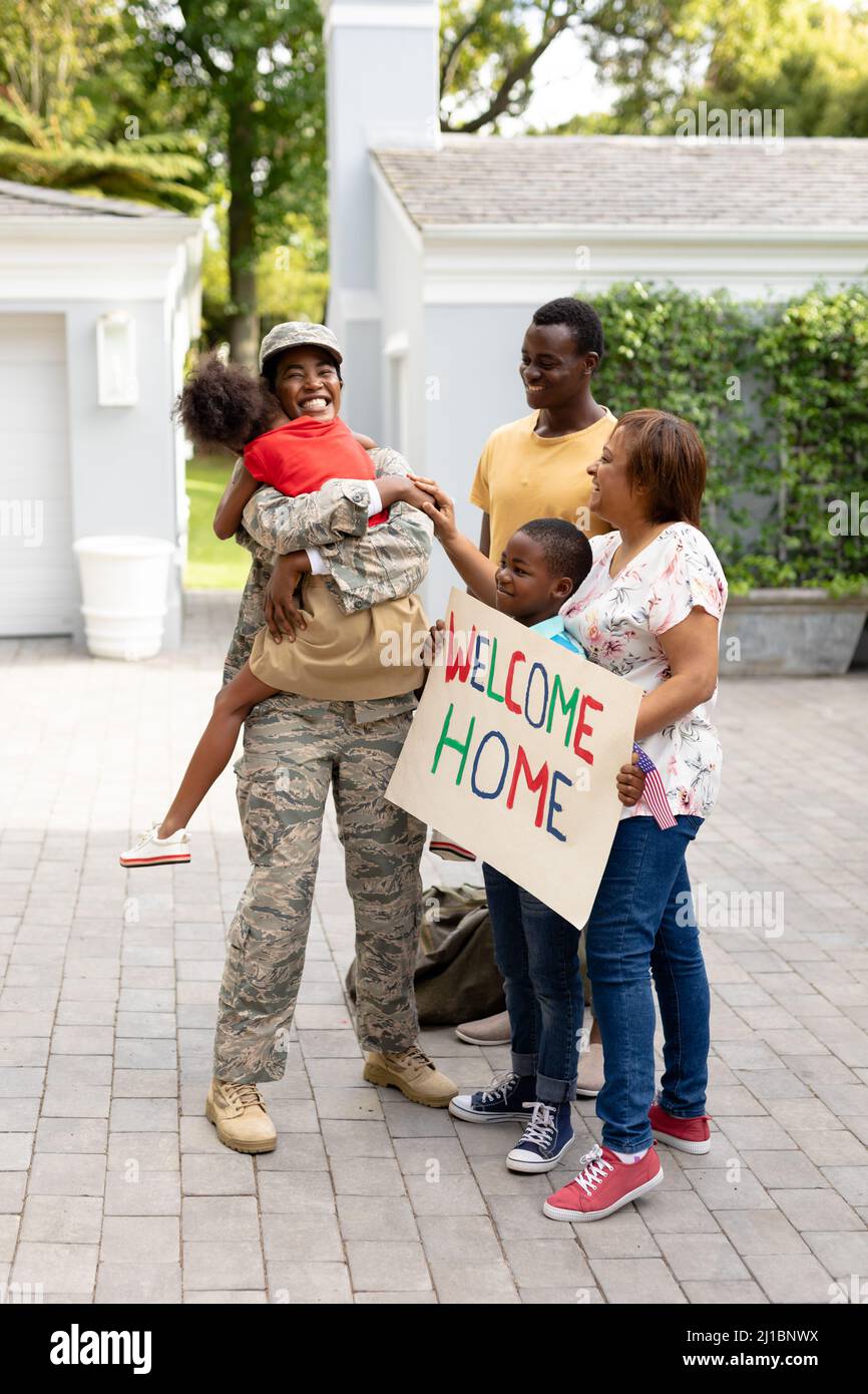 Happy female mid adult african american soldier embracing daughter while family welcoming her Stock Photo