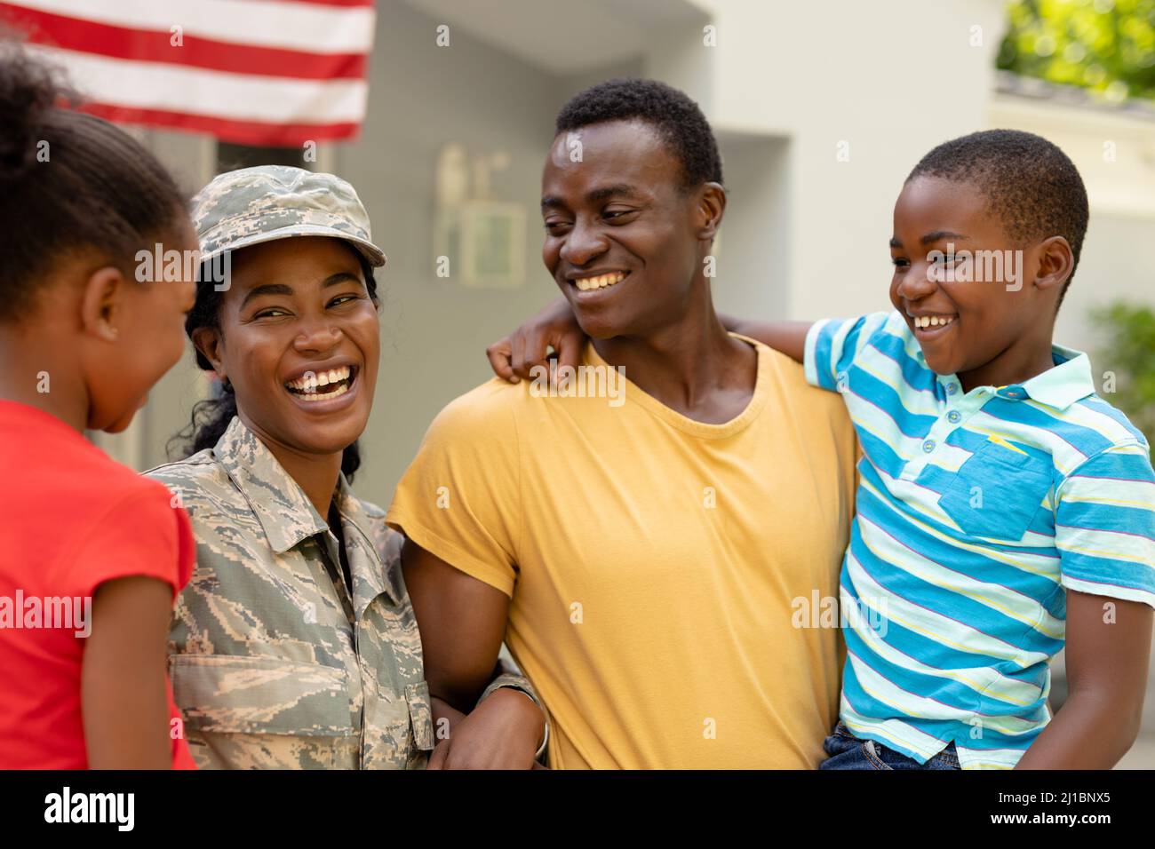 Cheerful female mid adult african american soldier with family outside house Stock Photo