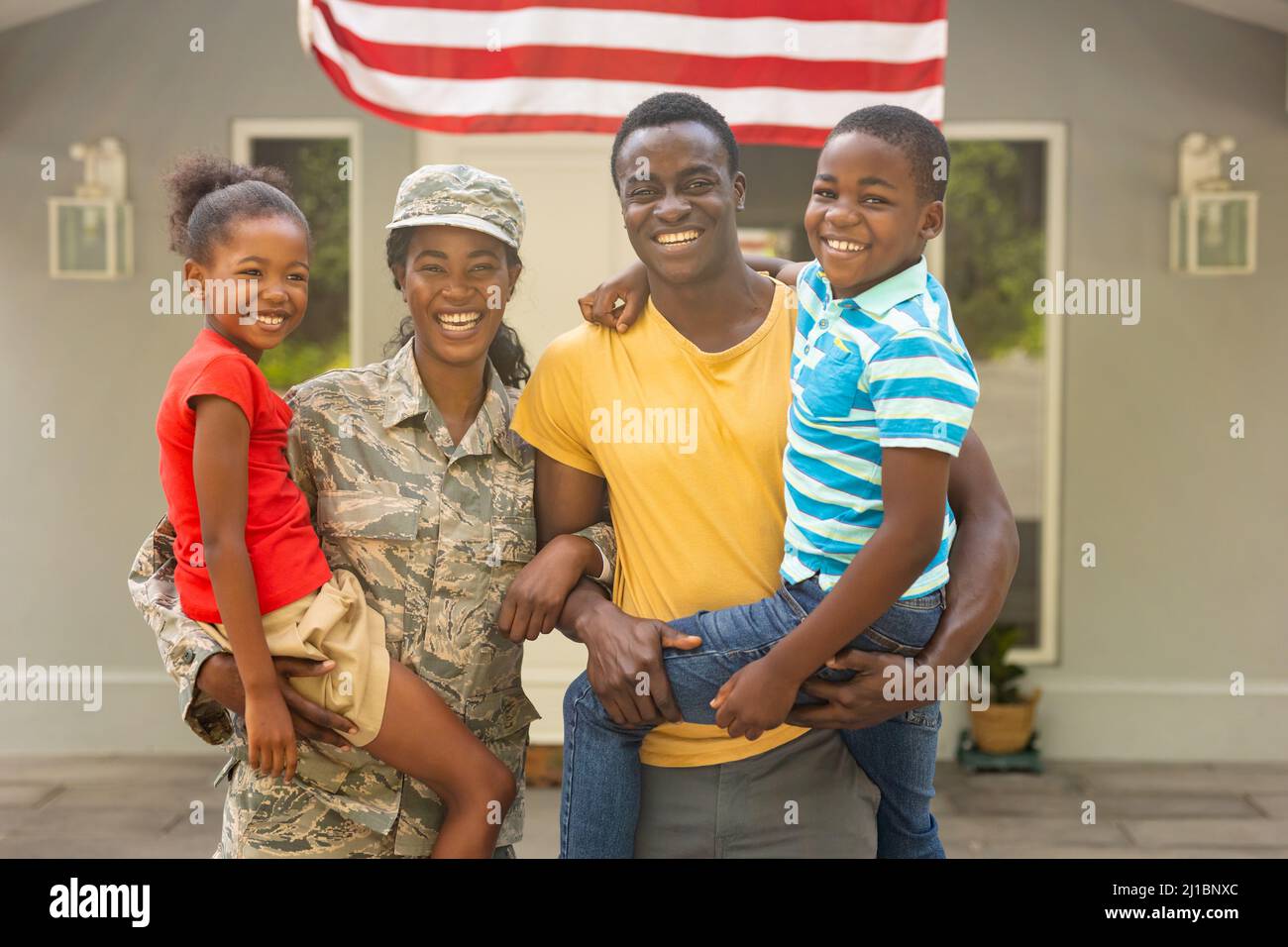 Portrait of happy female mid adult african american soldier with family outside house Stock Photo