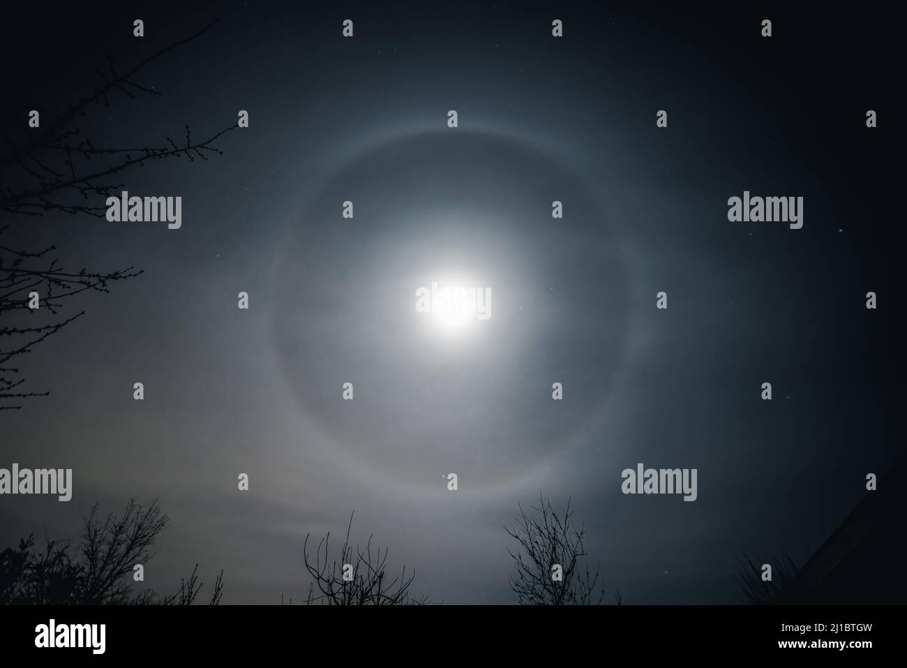 Moon halo ot moonbow clearly shown around the nearly full moon, late at night. Stock Photo