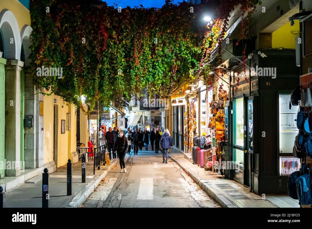 A picturesque street in the Plaka district of Athens Greece illuminated in the evening with plants and flowering trees covering the alley. Stock Photo