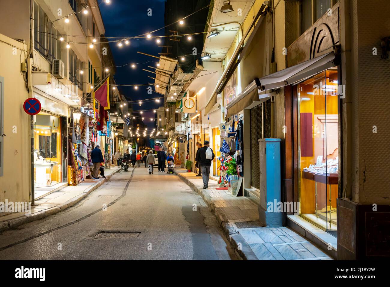 A colorfully illuminated narrow street of shops and cafes in the busy and touristic Plaka district of Athens, Greece at night. Stock Photo